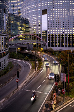 Traffic flows through La Defense Paris France beneath modern office buildings showing evening mobility and contemporary business district infrastructure