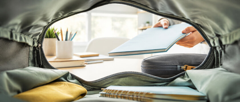 Back to school concept with person packing backpack in classroom background