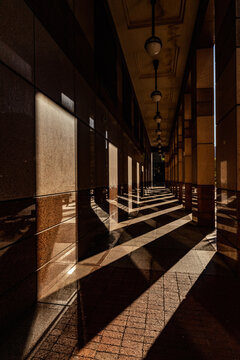 View of a modern colonnade with geometric shadows cast by pillars on the tiled floor in Cape Town, Western Cape, South Africa.