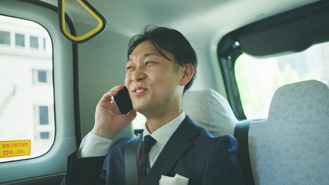 Smiling businessman having a phone conversation in a taxi
