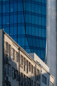 Older residential facade beside a modern blue glass tower in Warsaw Poland shows urban contrast between historic housing and contemporary architecture