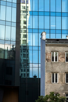 Historic residential building beside a modern blue glass tower in Warsaw Poland shows urban contrast between older housing and contemporary architecture