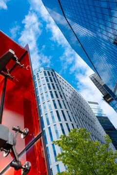 Modern towers and vivid red structures in Warsaw Poland create a dramatic low angle urban view with glass architecture blue sky and contemporary design