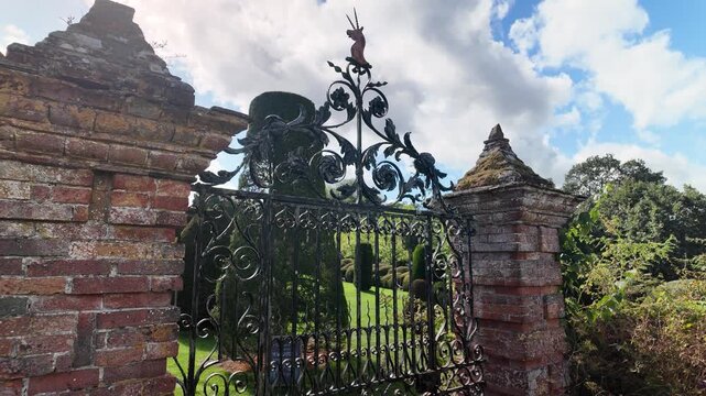 Ornate iron garden gate between old brick pillars