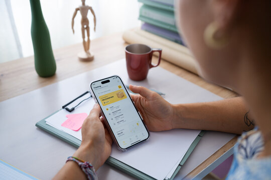 White person tracking package on phone at home office desk in a office