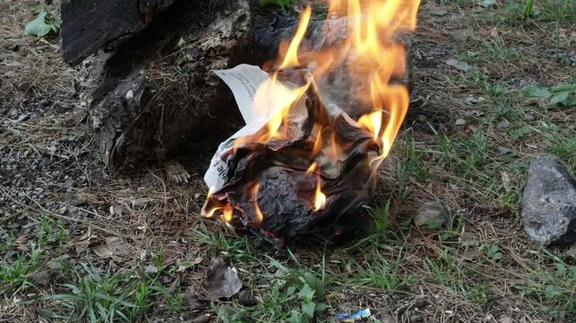 Fire Burning Newspaper on Ground with Flames and Smoke
