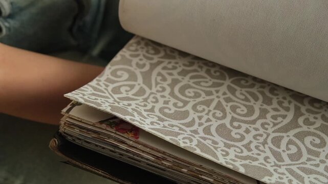 Close up of a female hand browsing fabric samples to choose material for roller blinds for home Interior design and window treatment concept focused on selecting colors textures and fabrics for decor