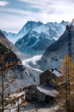 View of the Mont Blanc massif and Mer de Glace glacier with the Montenvers station, a construction crane, and tourists in Chamonix, Auvergne-Rhone-Alpes, France.