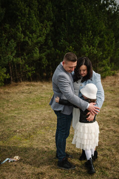 Happy family embracing each other warmly outdoors in a forest during a photo shoot.