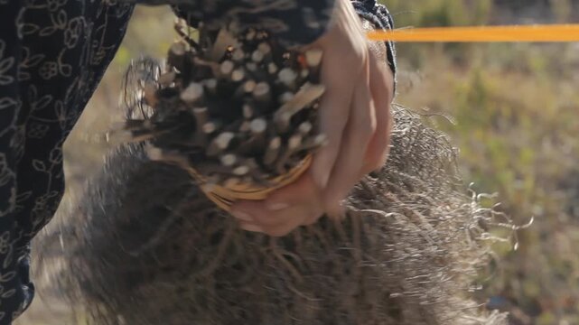 Close up of craftswoman hands tightly binding a traditional handmade broom made of natural twigs and brushwood outdoors