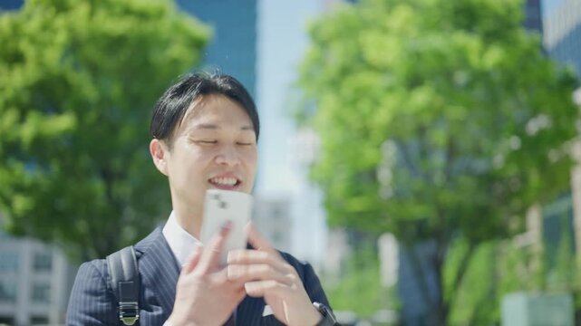 Businessman looking down while listening on a phone call outdoors