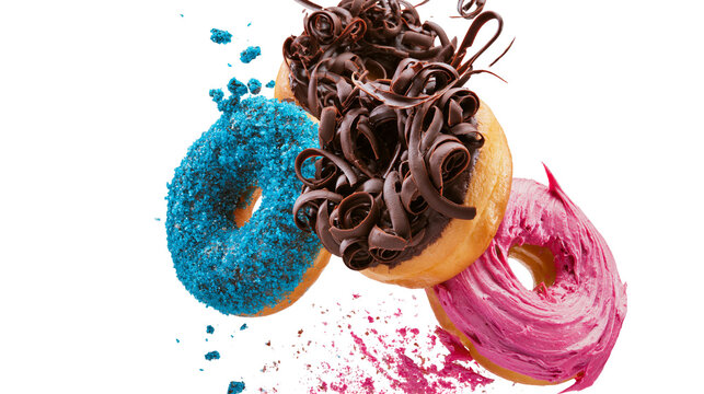 Isolated vibrant glazed donuts with falling blue sprinkles, chocolate curls, and pink frosting.