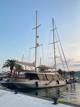 Classic two-masted wooden sailing yacht docked at a marina during twilight