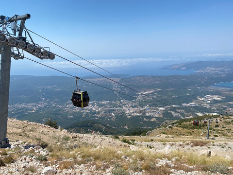 Cable car cabin hangs suspended on cables high above a coastal valley and bay