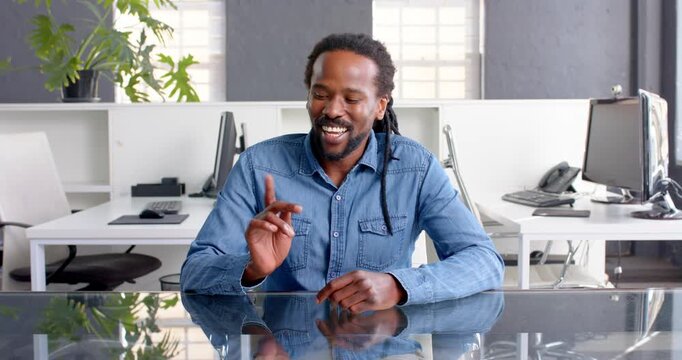 African American man in denim shirt smiling confidently at office desk