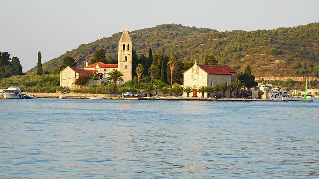 View of the historic Franciscan Monastery surrounded by the Adriatic Sea, waterfront, palm trees and Mediterranean landscape on a sunny summer day.