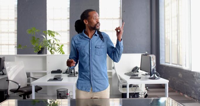 African American man in denim shirt speaking confidently in modern office