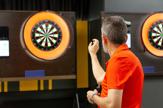 An adult athlete plays darts at a tournament