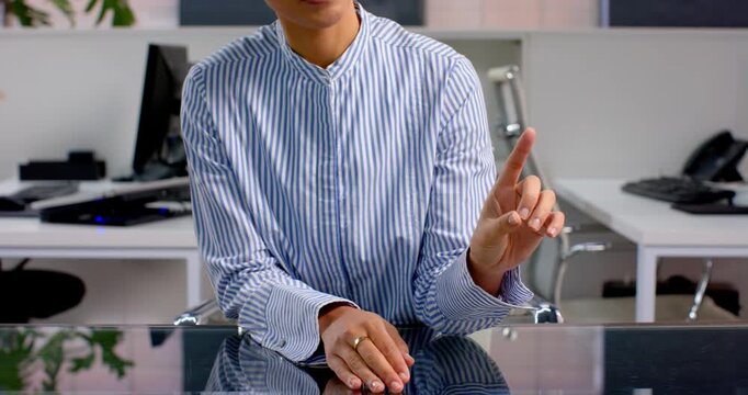 Businesswoman in striped shirt gesturing at office desk, making point