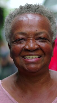 Close-up portrait of a senior African American woman outdoors, smiling with radiant warmth and kind eyes directly toward the camera
