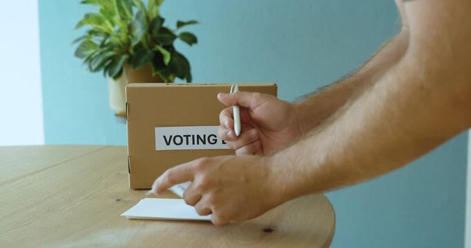 Man filling out a voting card and casting his vote into a voting box, representing election, democracy, choice and participation.