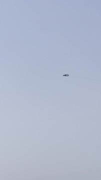 Twin-engine propeller airplane flies across a clear, pale blue sky