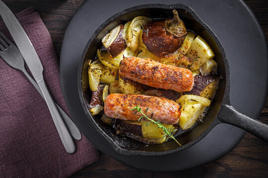 Sausages and vegetables are arranged in cast iron skillet