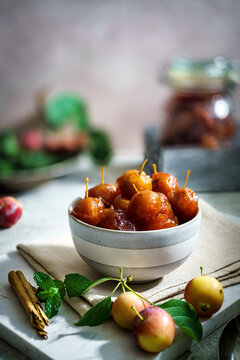 Whole crabapple preserves with stems attached on a rustic board