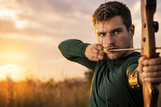 A focused male archer draws a wooden recurve bow while warm sunset light outlines his face and the nocked arrow. Precision sport