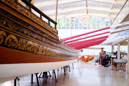 A historical wooden boat with ornate carvings displayed in a museum setting.