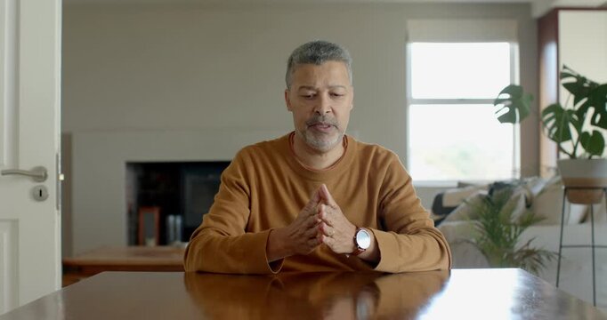 Senior man sitting at home, explaining something with hands, looking engaged and focused