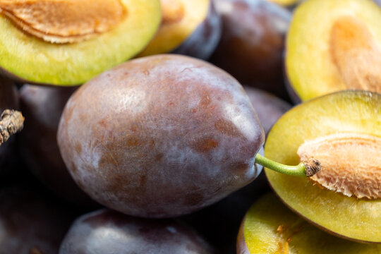 Ripe damson plums cut in half revealing inner seed texture.