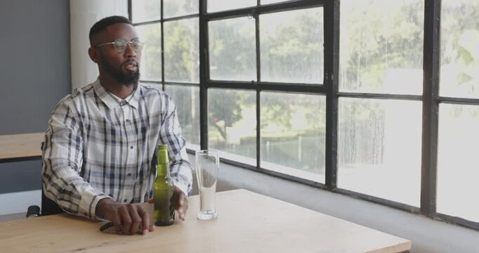 Man pouring beer into glass at office table, enjoying break from work