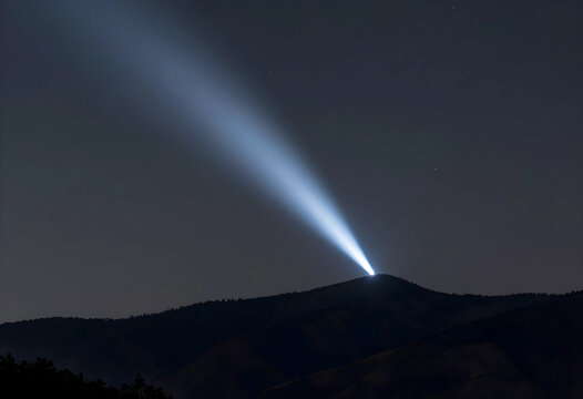 Guidance and hope concept bright searchlight beam shining from mountain peak into dark night sky vision leadership and future direction