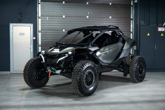 A fierce, desert-ready black BRP Maverick R XRC buggy on a solid black background. High-clearance suspension, massive tires, and aggressive racing frame under dramatic studio lighting. Peak off-road p