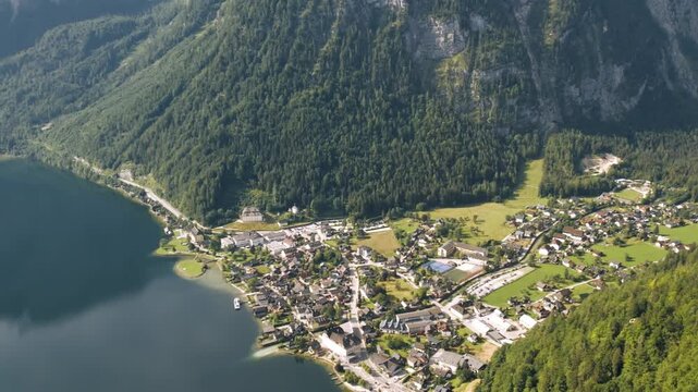 Aerial tilt up shot of lakeside village and mountains in Austria