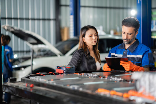 At the garage, customer and service technician read the battery report together with the insulation tester resting on the modules.