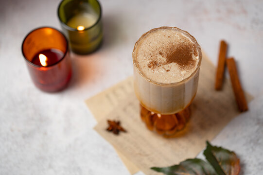 Autumn latte with spiced foam and cinnamon sticks, candlelit drink