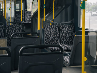 Empty public bus interior with modern seats, yellow handrails, and large windows on city route. © stas_malyarevsky