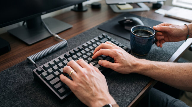 Person typing on keyboard while being distracted by coffee cup representing adhd attention