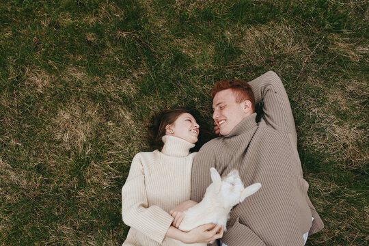 couple outdoor grass dog sweater cuddle love lifestyle romantic portrait happiness affection nature park relaxed smiling companionship moment harmony warmth serenity sunlight breeze cozy scene