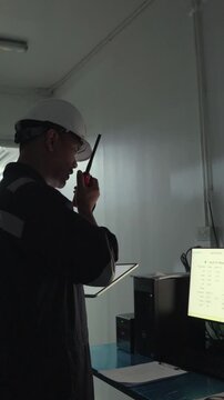 Environmental engineer communicating with team of technicians use radio and taking reports checking continuous emission monitoring systems at industrial plant. Sustainable air pollution reduction. ESG