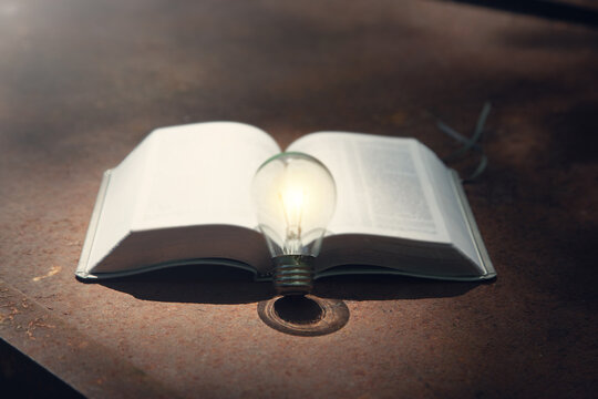 Light bulb and book on the old rusty background.