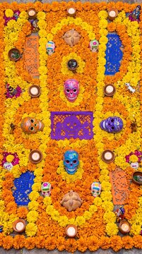 colorful day of the dead altar decorated with marigold flowers, sugar skulls, candles, and papel picado