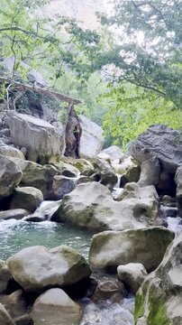 Vertical stock footage exploring a stunning mystical Turkish canyon with freezing crystal-clear turquoise waters and dramatic towering rock cliffs