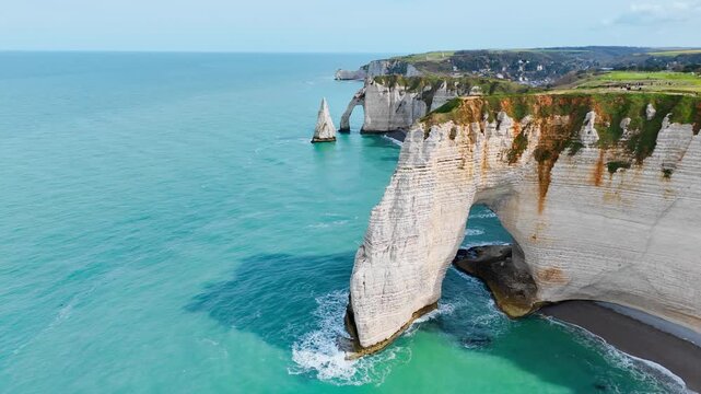 Etretat sea arch above turquoise water in Normandy, France. Aerial footage of white chalk cliffs with Aiguille d Etretat in distance