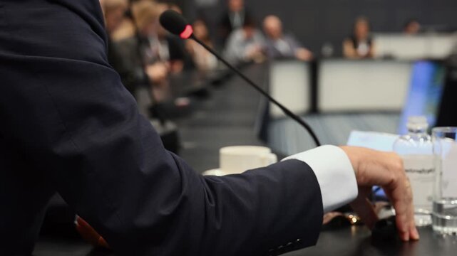 Close up of a conference speaker with microphone addressing an audience at a professional event. Universal concept of public speaking, presentation, discussion and communication.