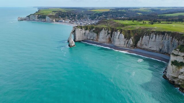 Etretat chalk cliffs in Normandy, France. Aerial footage of natural arch and Aiguille d Etretat beside turquoise sea