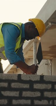 Bricklayer, black man and building with tool for construction, boundary wall or property extension. Worker, mature block mason or trowel on site for remodeling, manual labor or mortar for bricklaying