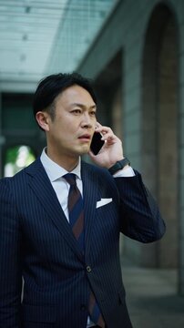 Japanese businessman on the phone in a shaded office building arcade